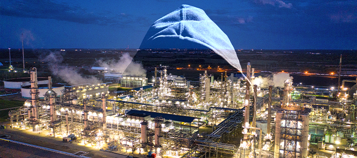 A hooded figure looks over an oil and gas facility
